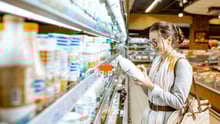 Una consumidora elige leche vegetal en un supermercado.