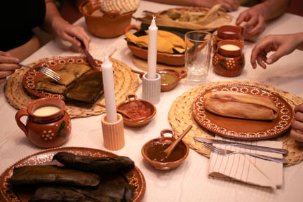 Personas cenan en una mesa con tamales mexicanos veganos.