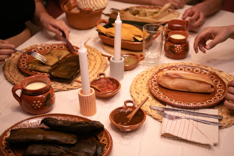 Personas cenan en una mesa con tamales mexicanos veganos.